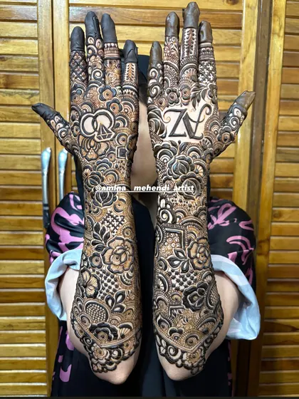 The complete look for this engagement mehendi, with full coverage on both arms featuring a mix of florals, paisleys, and personalized 'AZ' initials.