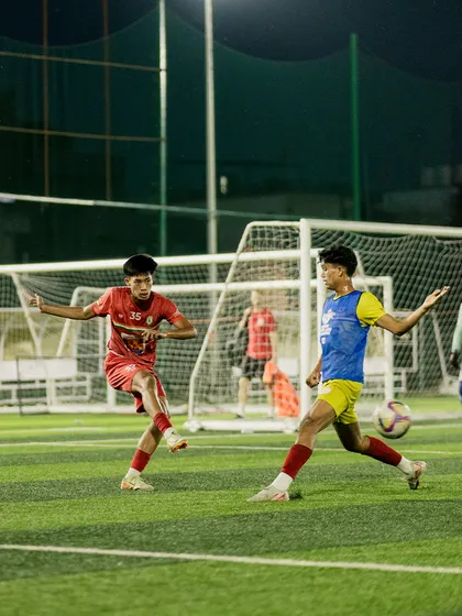 Two players challenge for the ball in a competitive drill. These 1v1 situations are crucial for developing both defensive and offensive skills under pressure.