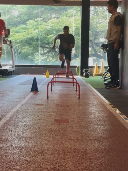 A coach watches as a client performs hurdle drills. This supervision ensures the client is performing the drill correctly for maximum benefit.