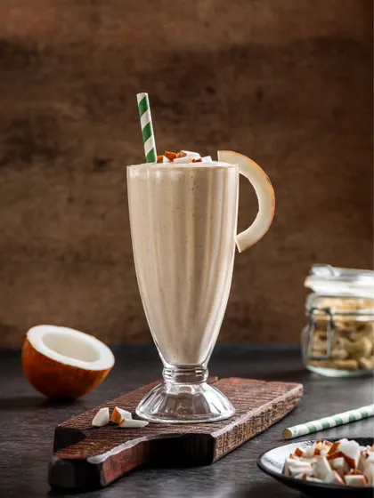 A coconut-flavored milkshake, garnished with a slice of dried coconut, offering a tropical vibe.