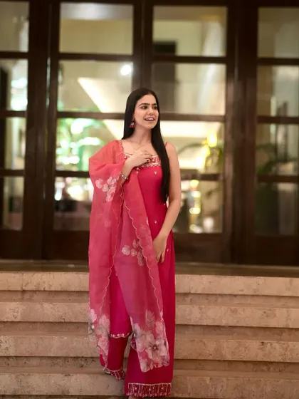 A full-length shot of the pink kurta set on a staircase, showing its elegant and traditional design.