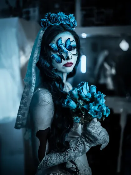 A portrait of the Corpse Bride with her bouquet of blue roses. The butterfly details on the face add a touch of delicate artistry to this spooky look.