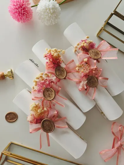 The finished Devanagari wedding invitations, rolled into scrolls and adorned with dried flowers, ribbons, and wax seals. Despite a setback, I remade each one to ensure they were perfect.