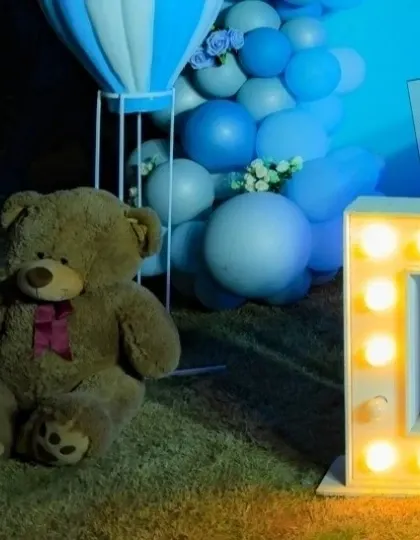 A close-up detail shot of the teddy bear and marquee number at Daksh's party.