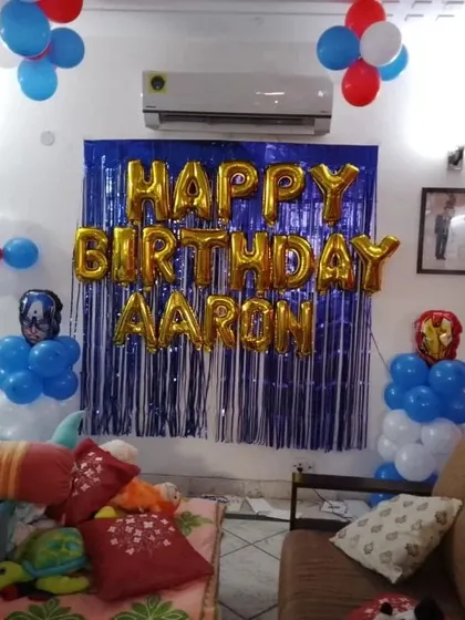 A simple yet effective Avengers-themed room decoration for a birthday surprise. The setup uses a blue foil curtain backdrop, "Happy Birthday" foil letters, and balloon columns topped with Captain America and Iron Man foil balloons.