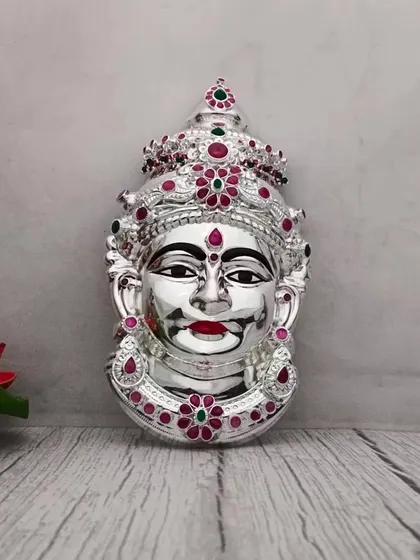 A pure German silver Lakshmi face with intricate stone work. The silver shine gives it a very pure and divine feel.