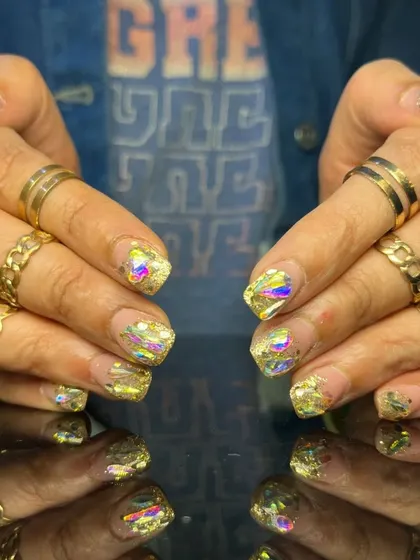 A bold and glamorous set of short, square nails with a shattered glass effect using iridescent gold foil.