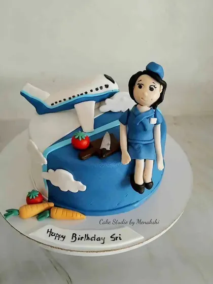 A birthday cake customized for a cabin crew member at Indigo Airlines. The design includes a plane, a handcrafted figurine in uniform, and healthy vegetables.