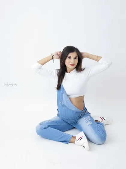 A fun and energetic portrait of a mom-to-be in denim overalls. Her playful pose and happy expression are infectious.