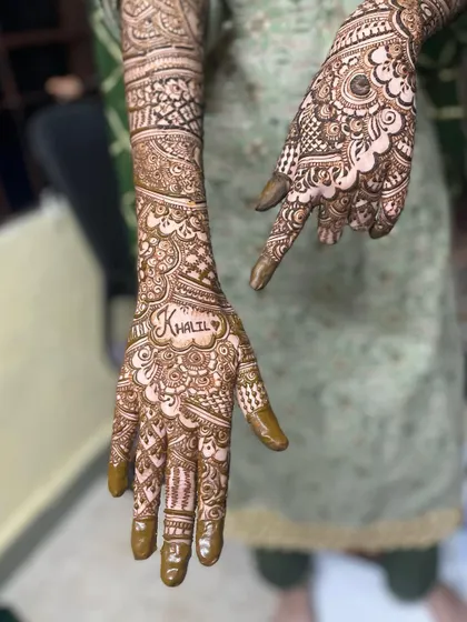 This engagement mehendi includes the groom's name, 'Khalil', hidden within the intricate pattern. It's a sweet, personal touch.