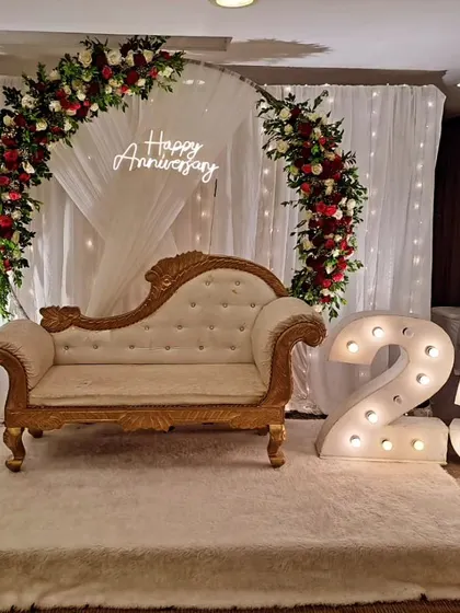 A full view of the 25th-anniversary decoration for Mr. Ravi and Mrs. Preeti. The combination of a fresh floral arch, neon sign, and marquee numbers makes for a stunning tribute to their journey.