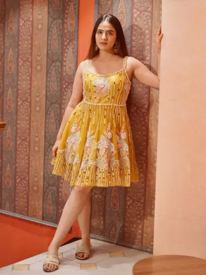 A full view of this adorable short yellow fusion dress. It's the perfect mix of desi details and western silhouette for a fun, festive look.