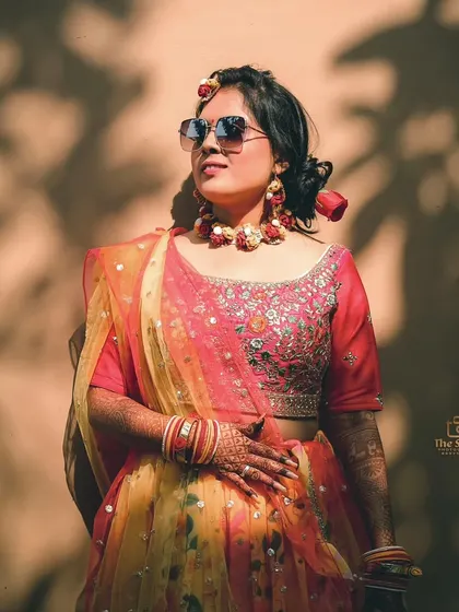 A stylish bride enjoying the sun at her outdoor Haldi ceremony. The play of light and shadow on the wall creates a beautiful, natural pattern.