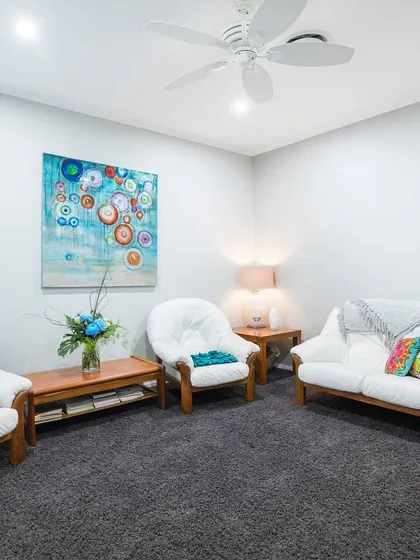 A simple sitting room with clean white walls. This provides a versatile backdrop that allows the colorful furniture and artwork to stand out.