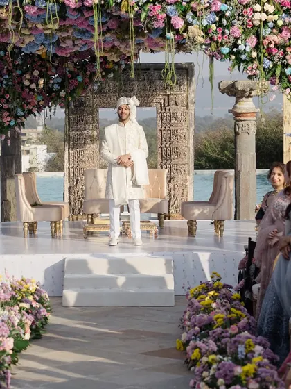 The groom awaits his bride under a stunning floral mandap. I designed this aisle with lush, low floral arrangements in pastel hues to create a beautiful pathway, building anticipation for the bride's grand entrance.