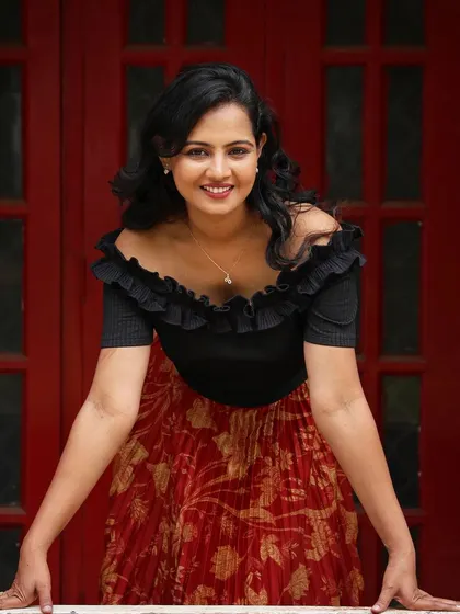 A vibrant outdoor portrait. The makeup is warm and glowing, with a soft smile that brings out the client's personality against the bold red background.