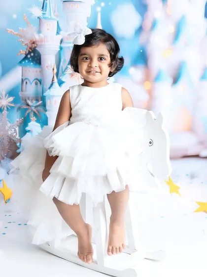 This little princess is all smiles on her rocking horse. The winter castle backdrop creates a truly enchanting setting for a milestone photoshoot.