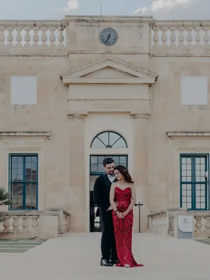 A classic portrait of the couple standing before a grand Maltese building, showcasing the timeless elegance of their pre-wedding shoot.