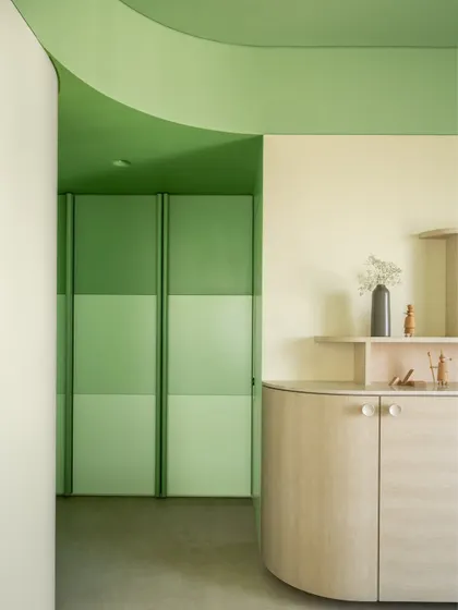 A detail of the son's bedroom, where a curved wall and color-blocked green tones create a dynamic and playful entrance to the space.