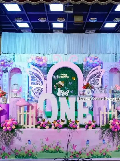 A full stage view of a butterfly fairy tale theme, complete with flamingo props and a large 'ONE' centerpiece.