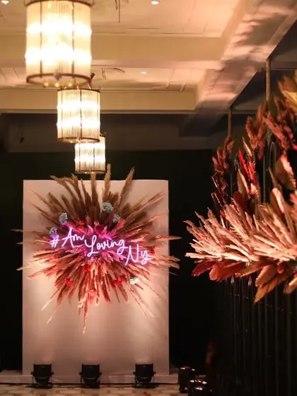 The entrance corridor leading to the pampas grass photo wall, with hanging floral installations creating a dramatic and textured effect.