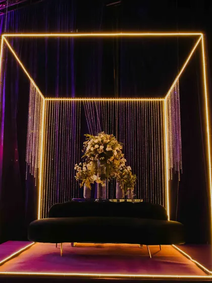 A modern and chic photo booth for a sangeet night. I designed this illuminated neon cube with a backdrop of crystal strings, creating a perfect spot for couples and guests to capture stylish memories. The plush sofa and floral arrangement add a touch of elegance.