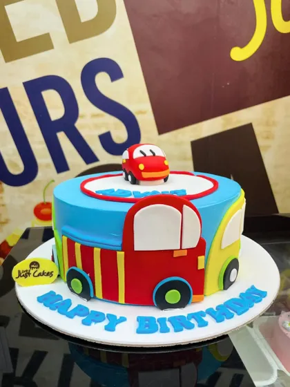 A colorful 1.5kg car theme cake with fun, cartoonish cars decorating the side.