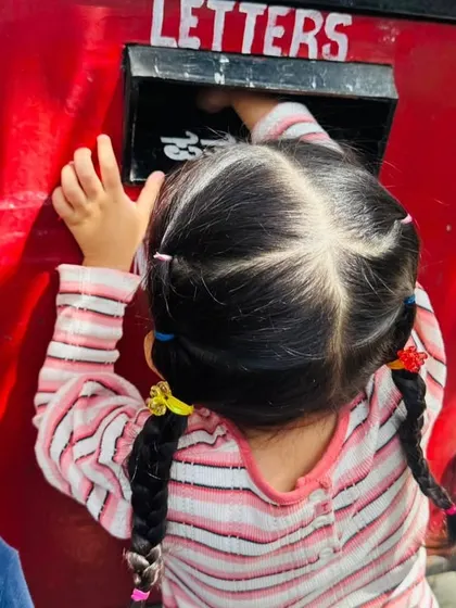 Another student reaches into the postbox, thrilled to be part of the process of sending mail.
