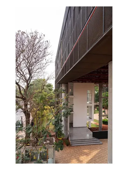 The building's screened facade creates a portal-like entrance to the campus. The linear screened box is experienced through the foliage of existing trees.