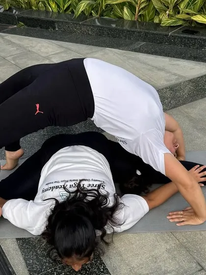 This partner pose combines a deep forward fold (Upavistha Konasana) with a full backbend (Chakrasana). It's an advanced expression of flexibility and mutual support.
