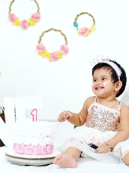 A sweet moment just before the smash. This little girl, dressed in a beautiful sequin dress, smiles beside her first birthday cake in our studio, ready for her celebratory photoshoot.