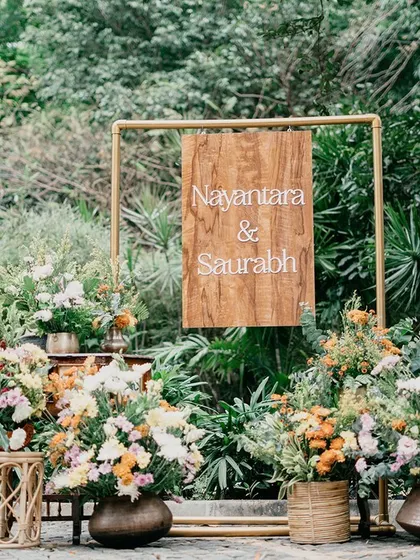 A simple wooden welcome sign surrounded by beautiful, rustic floral arrangements, perfectly suited for a garden or farmhouse wedding.