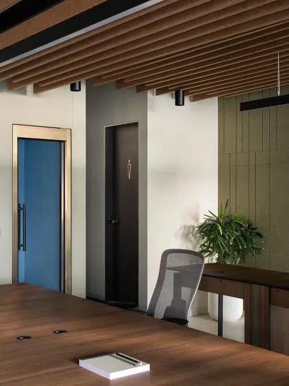Even functional elements are considered in our design. The doors are integrated into the overall aesthetic, with a bold blue door adding a pop of color and a dark wood door featuring a minimalist brass sign for the restroom.