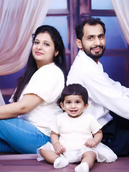 A classic seated family portrait with a smiling baby girl at the center.