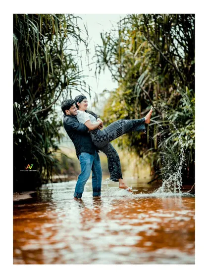 A playful and joyful moment as the groom lifts his partner and splashes in the water.