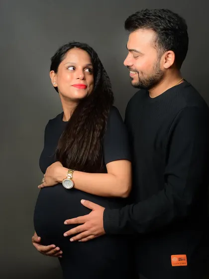 A classic maternity pose, with the couple looking at each other, their hands on the baby bump, sharing a moment of connection.