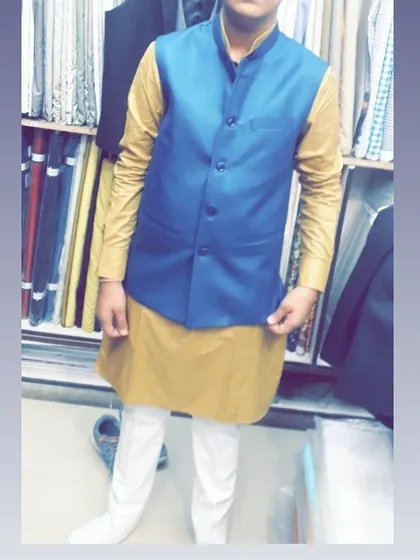 A client trying on a bright blue Nehru jacket over a mustard kurta in my shop. I help my clients mix and match to find the perfect combination.