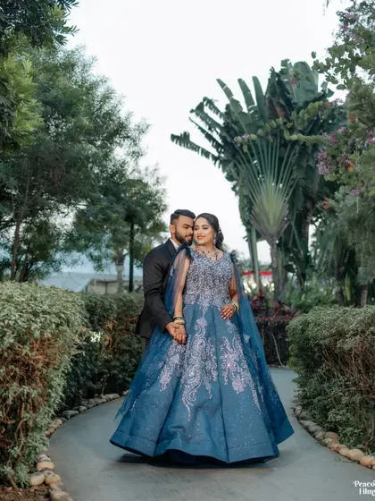 A fairytale portrait of the couple in a lush garden. The bride's magnificent blue gown and the groom's classic tuxedo create a look of pure elegance.
