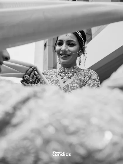 A black and white candid shot of the bride sharing a happy, genuine smile with her groom, framed in a way that feels like a stolen, private moment.