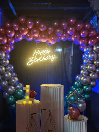 Another angle of the heart-shaped balloon arch for a first birthday. The chrome balloons catch the light beautifully, and the neon sign adds a modern touch.