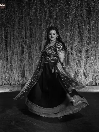 A beautiful black and white action shot of a bride twirling in her lehenga during her Sangeet or reception. The motion of the skirt and her joyful expression are captured perfectly.