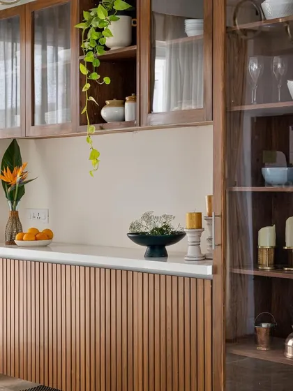 This crockery unit features fluted wooden paneling and glass display cabinets, blending storage and style.