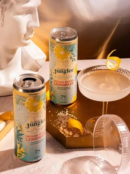 A sophisticated setup for Junglee's Indian Spiced Lemonade, showing the cans alongside a prepared cocktail. This suggests the product's versatility.