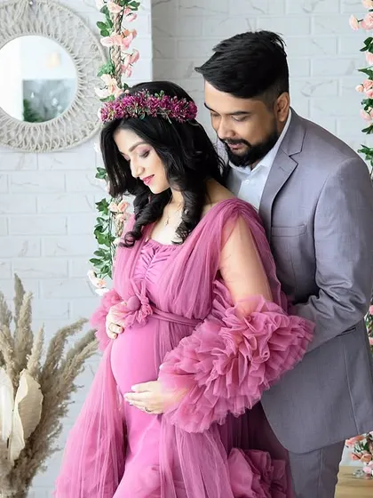 An intimate couple's portrait in our boho-chic setup. The partner gently embraces the mom-to-be, who is wearing a lovely dusty rose ruffled gown and floral crown.