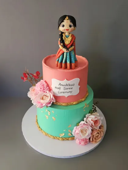 All dolled up to celebrate womanhood. This two-tier cake for Anushika's Half Saree ceremony features a beautiful, hand-sculpted figurine in a traditional lehenga.