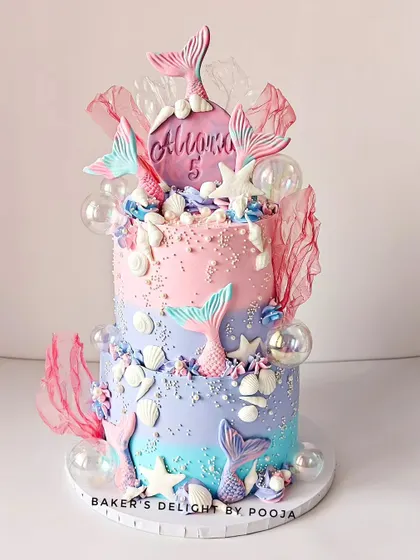 This two-tier mermaid cake is a pastel dream, with soft pinks, purples, and blues. Decorated with mermaid tails, seashells, and magical bubbles, it's perfect for celebrating a fabulous fifth birthday.