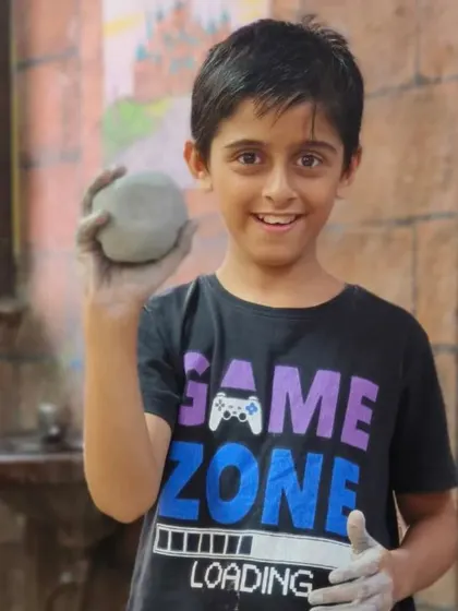 A young boy holds up a perfectly round ball of clay, the first step for any pottery project. Our classes build skills from the ground up.