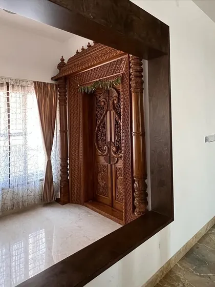 An intricately carved wooden pooja room door, framed as a piece of art within a modern home, celebrating traditional craftsmanship.