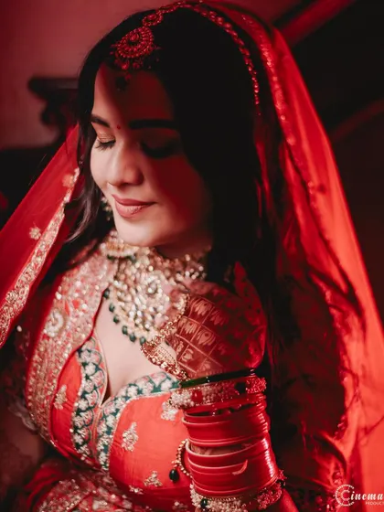 A close-up bridal portrait bathed in dramatic red light, emphasizing her beautiful features and the rich color of her attire.