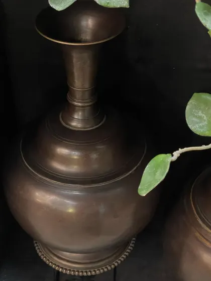 A close-up of the large copper vase, showing the texture of the vintage finish and the elegant curve of its neck. This is a substantial, handcrafted piece that adds a touch of rustic luxury.